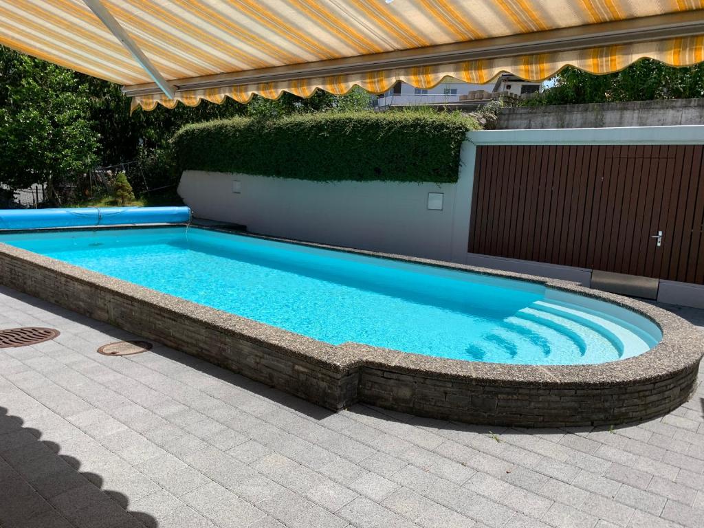 a large swimming pool in a patio with an umbrella at Hotel Krone in Attinghausen