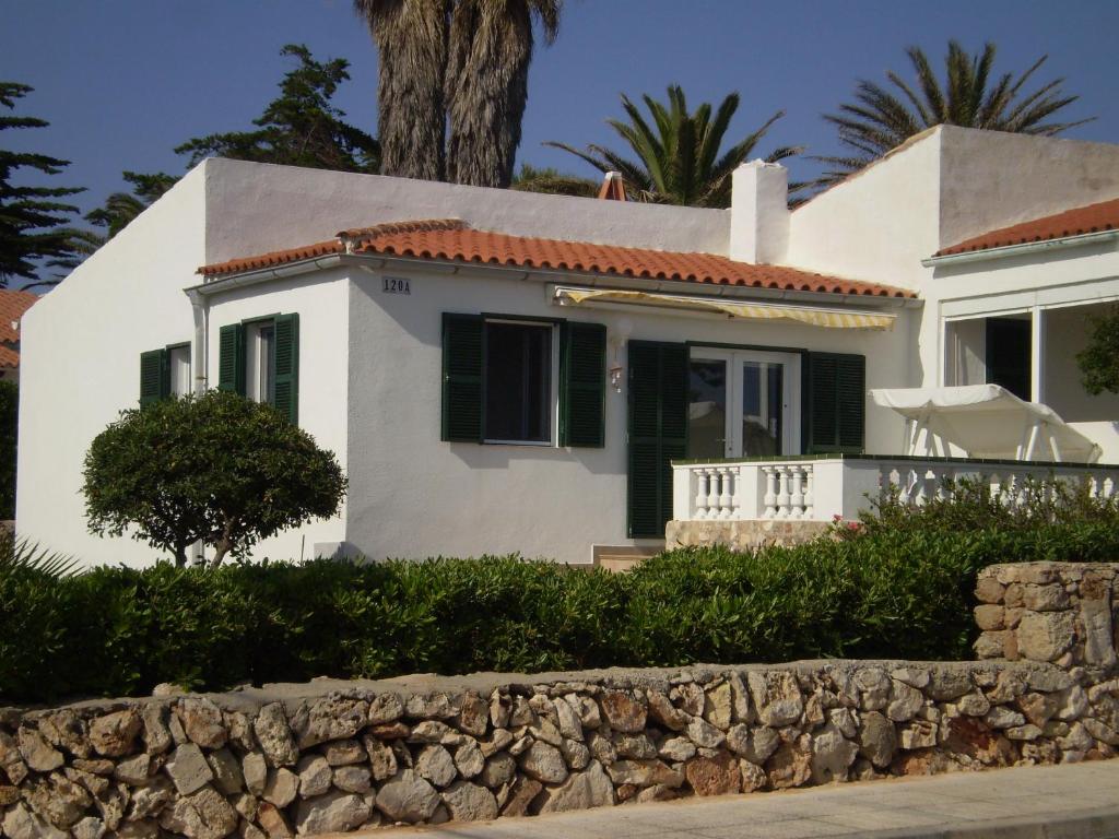 ein weißes Haus mit einer Steinmauer davor in der Unterkunft Ferienhaus nahe am Meer in Sant Lluís