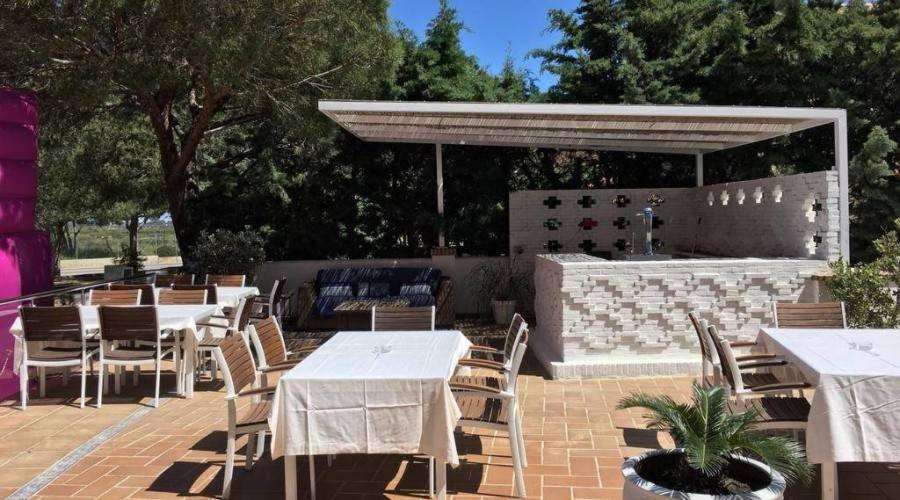 a patio with tables and chairs and a bar at Hotel Marisma Sancti Petri in Chiclana de la Frontera