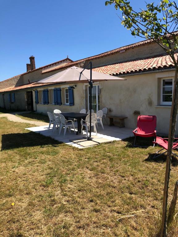 un patio avec une table et des chaises devant une maison dans l'établissement La Bénetière, à Saint-Valérien