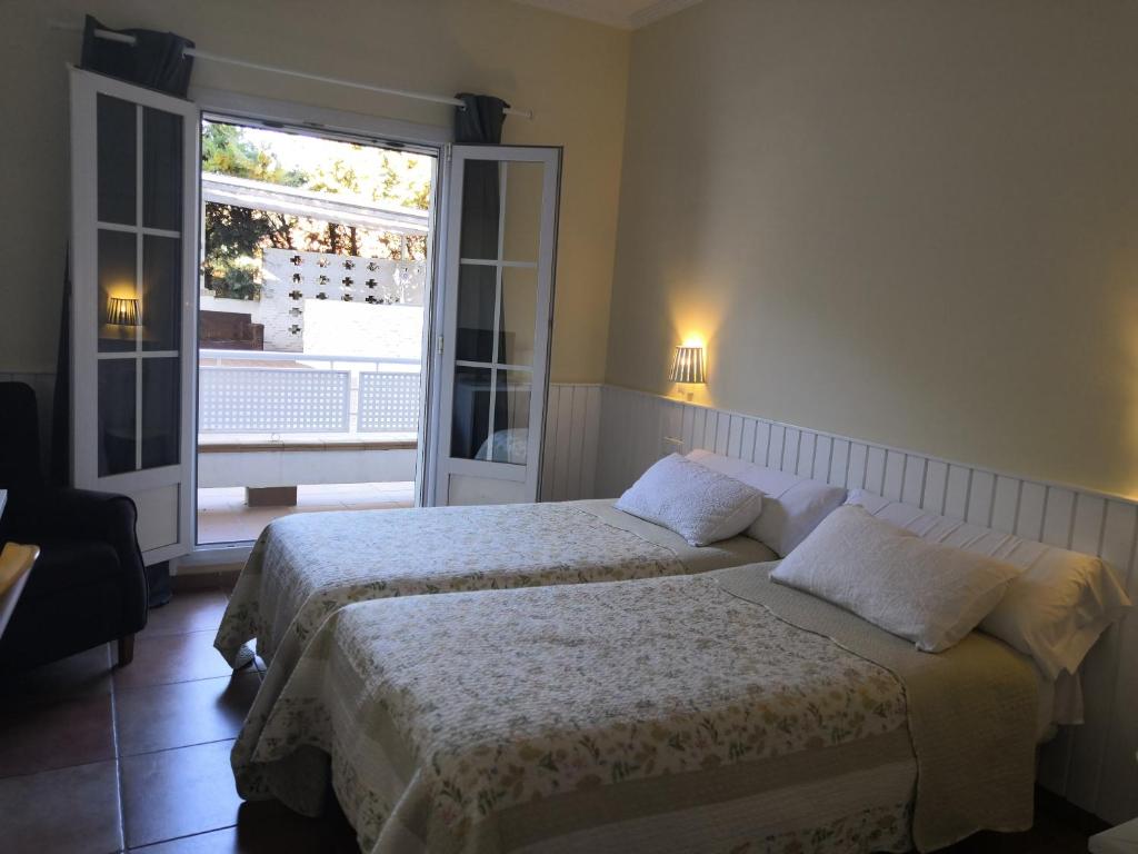 a bedroom with two beds and a large window at Hotel Marisma Sancti Petri in Chiclana de la Frontera