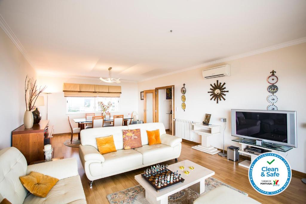 a living room with a white couch and a tv at WHome | Ericeira Luxury Apartment in Ericeira