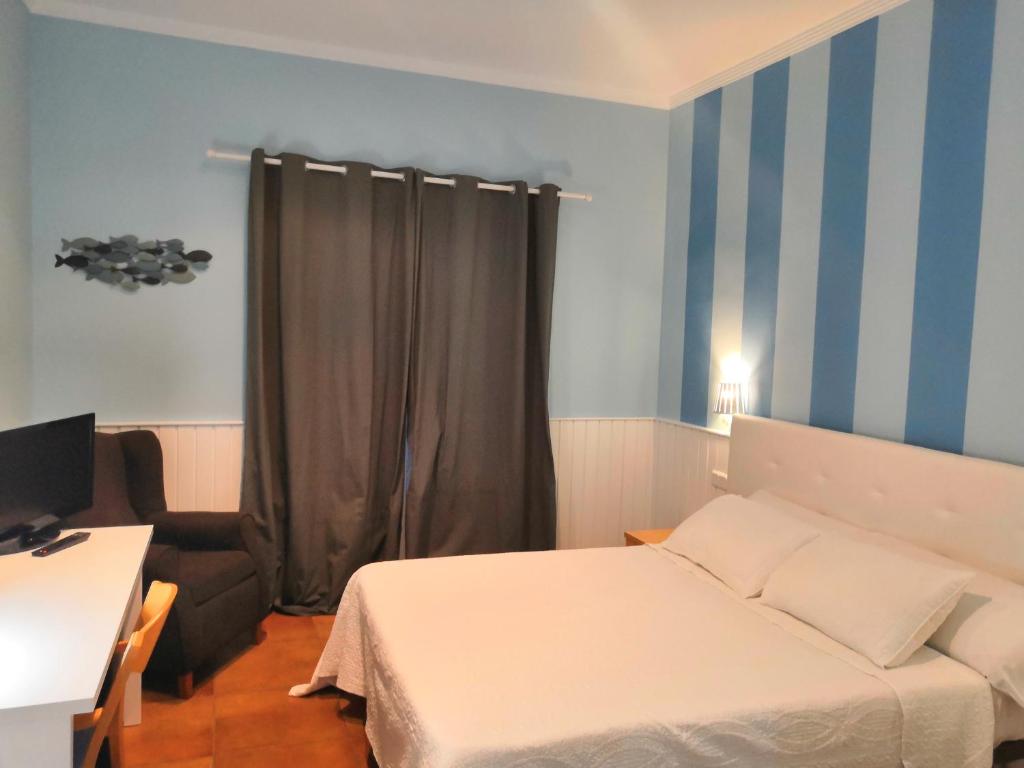 a bedroom with a bed and a desk with a monitor at Hotel Marisma Sancti Petri in Chiclana de la Frontera