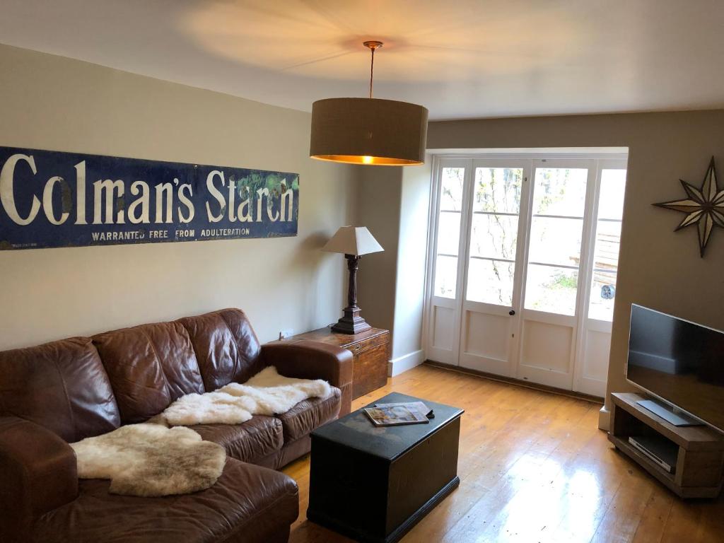 a living room with a leather couch and a television at Little Doric in Shepton Mallet