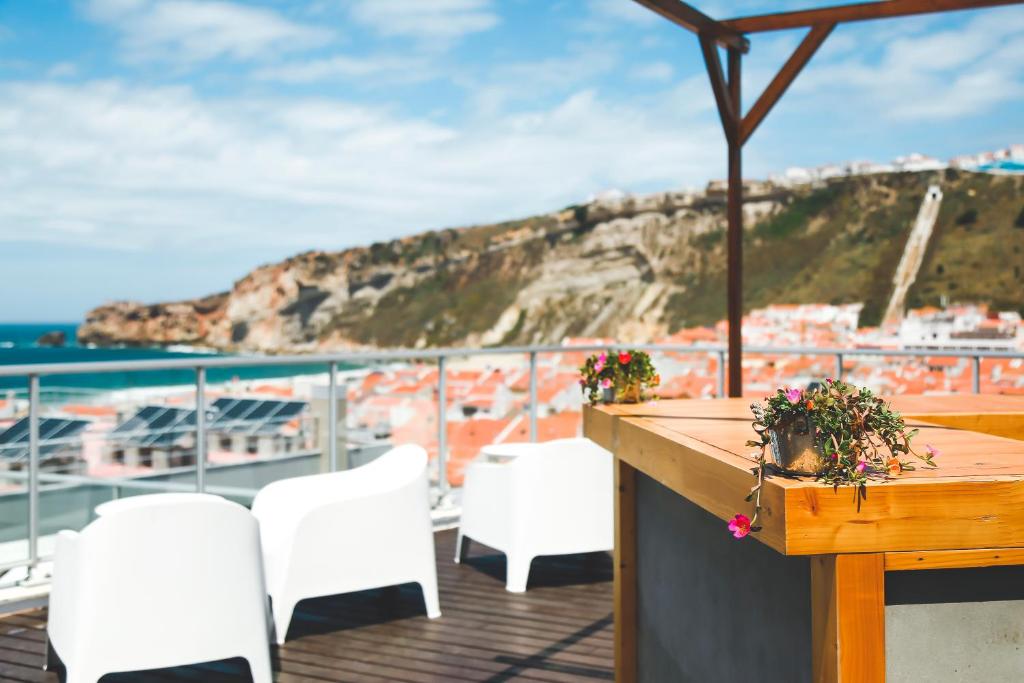 a table and chairs on a deck with a view of the ocean at Hotel Praia in Nazaré