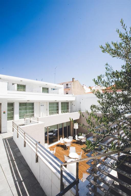 a large white building with a balcony with a table at Hotel Praia in Nazaré