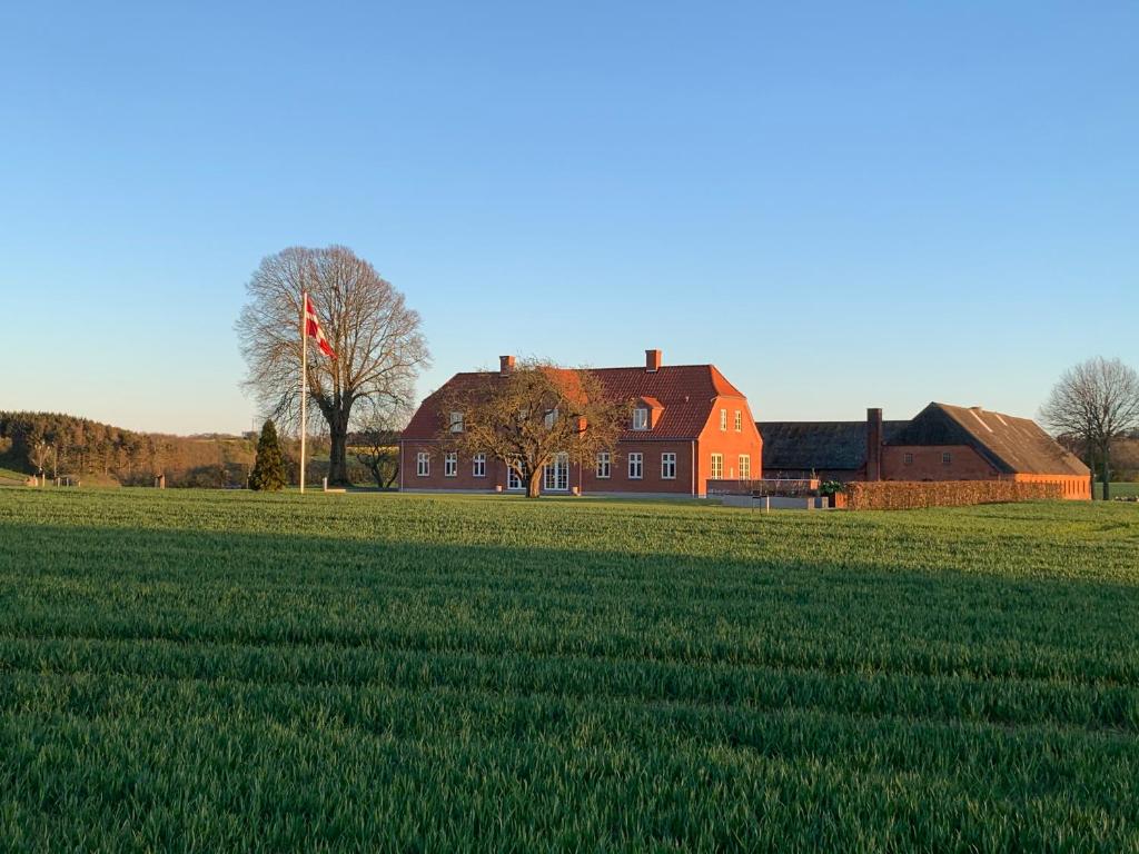 a large red house in a field of green grass at Meldbjerg in Stouby
