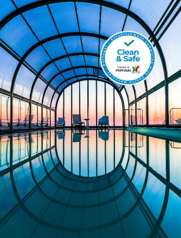 a circular building with a pool of water with a sign at Hotel Praia in Nazaré