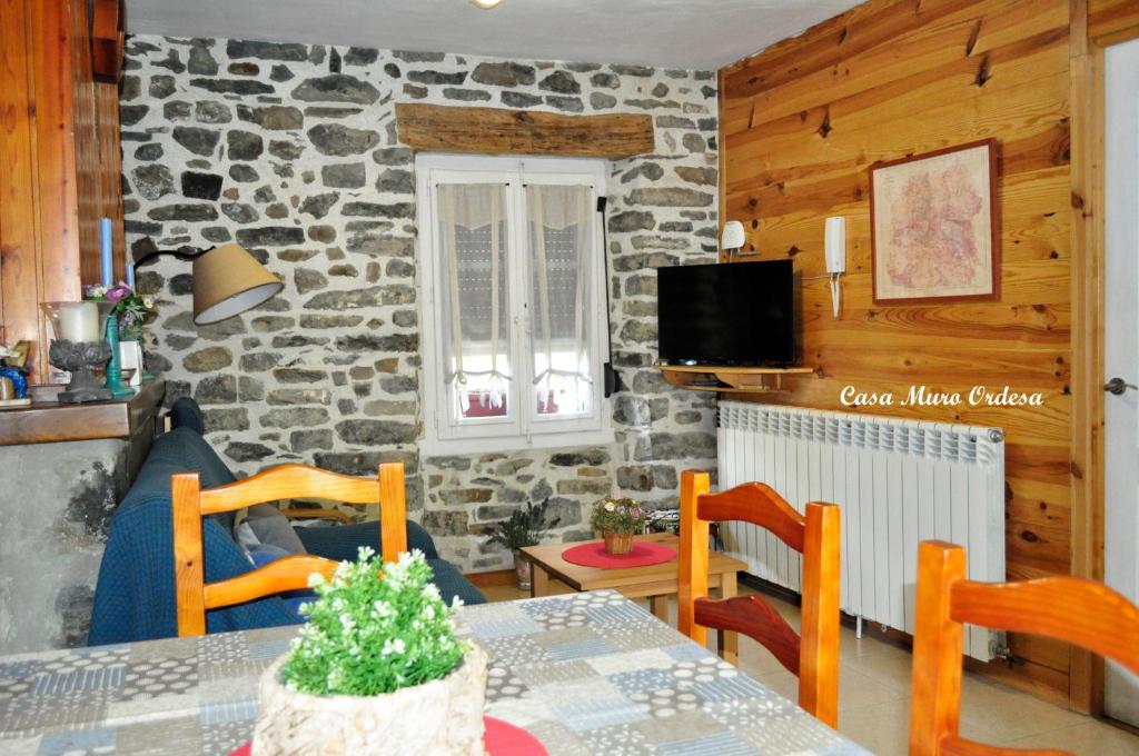 sala de estar con mesa y pared de piedra en Casa Muro Ordesa, en Frajén