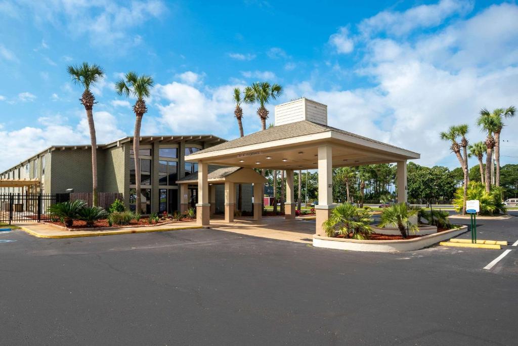 a parking lot in front of a building with palm trees at Quality Inn in Fort Walton Beach