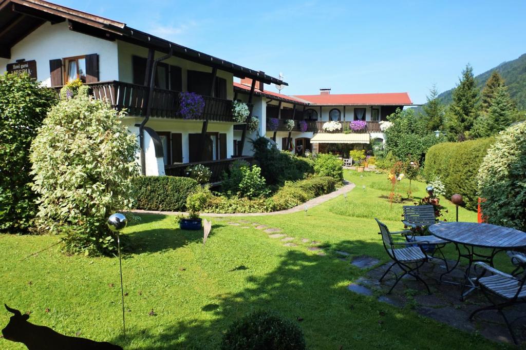 ein Haus mit einem Garten mit einem Tisch und Stühlen in der Unterkunft Hotel Garni Liberia in Oberstdorf