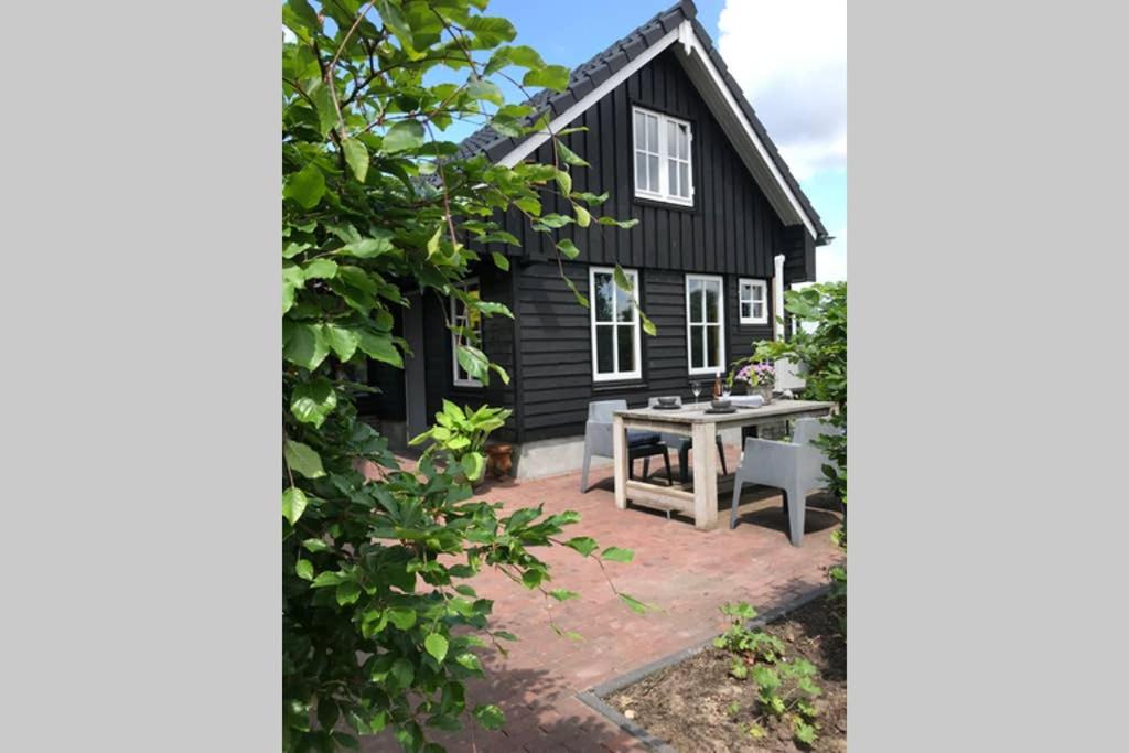 a black house with a picnic table in front of it at Uniek houten huis nabij bos en plassen in Hollandsche Rading