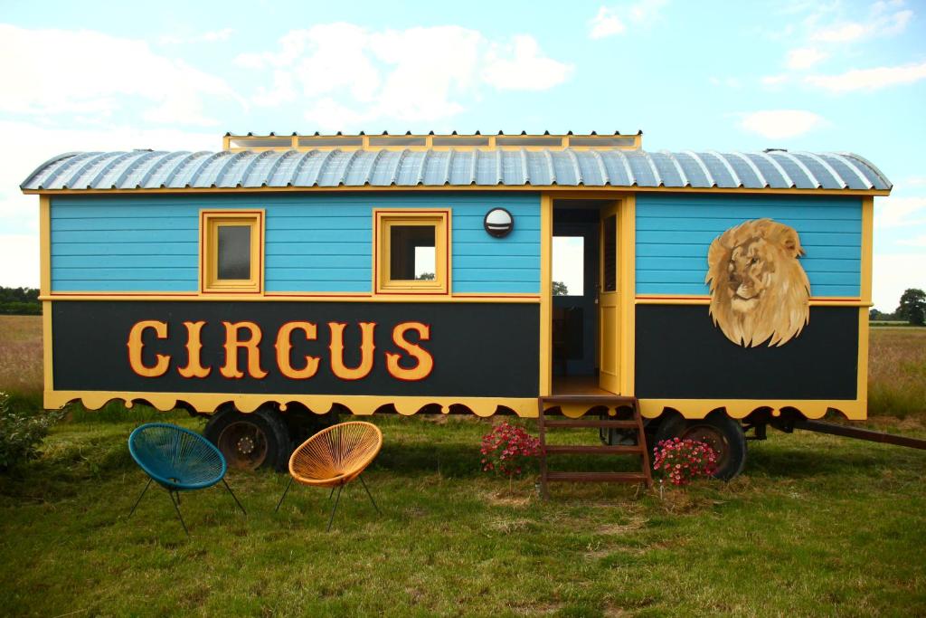 a blue and yellow train car on display in a field at La roulotte CIRCUS des Grillots in Beaulon