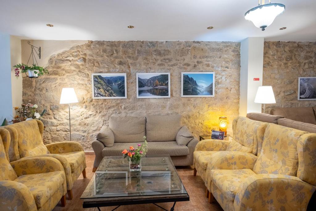 una sala de estar con sofás y una pared de piedra. en Hotel La Jara-Arribes, en Aldeadávila de la Ribera