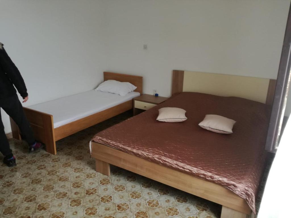 Dos camas en una habitación pequeña con alguien parado al lado. en Apartment Jerkovic en Klek