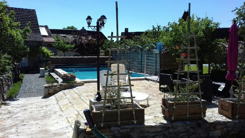 un patio trasero con piscina y algunas plantas en cajas en Chambre d'hôtes le chat botté en Espédaillac
