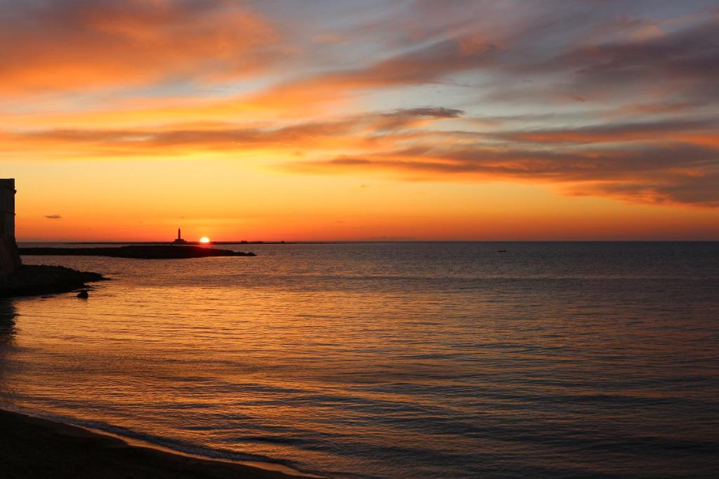 un tramonto sull'oceano con un faro in lontananza di B&B Incanto Salento a Ugento