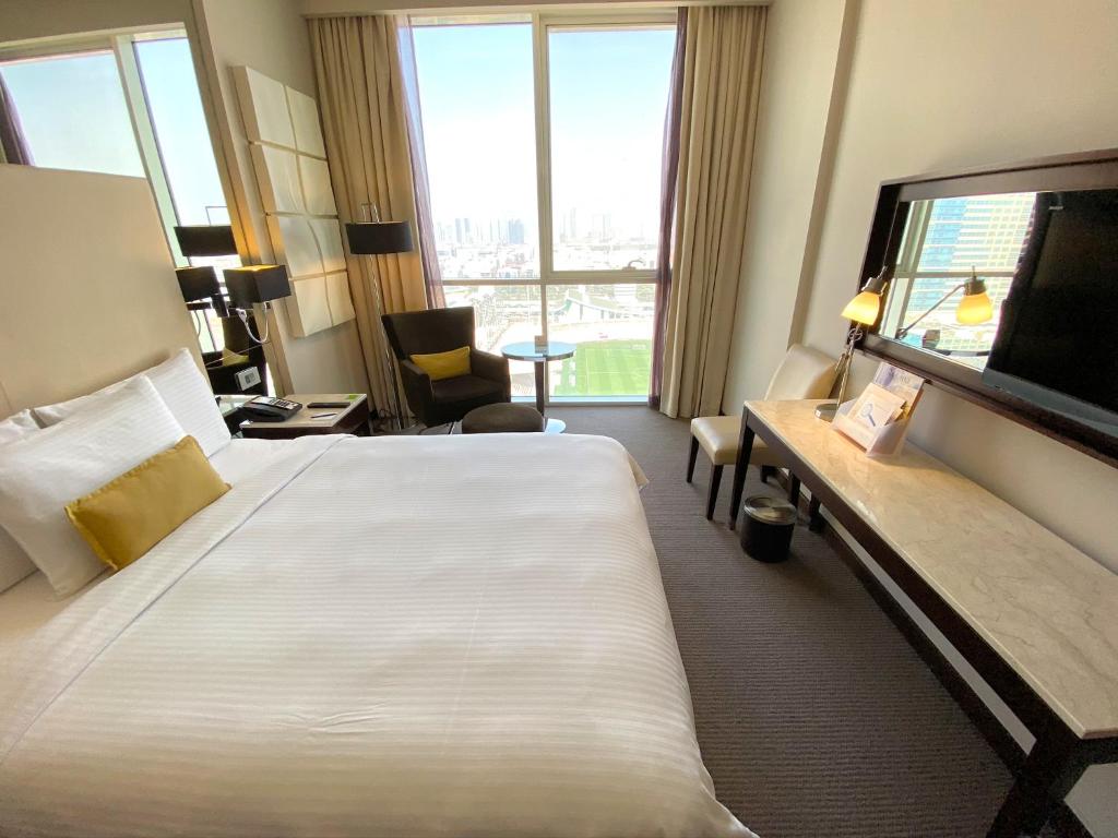a hotel room with a large bed and a large window at Centro Al Manhal by Rotana in Abu Dhabi