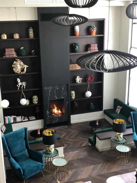 a living room with a fireplace and blue chairs at Hôtel La Villa Port d'Antibes & Spa in Antibes