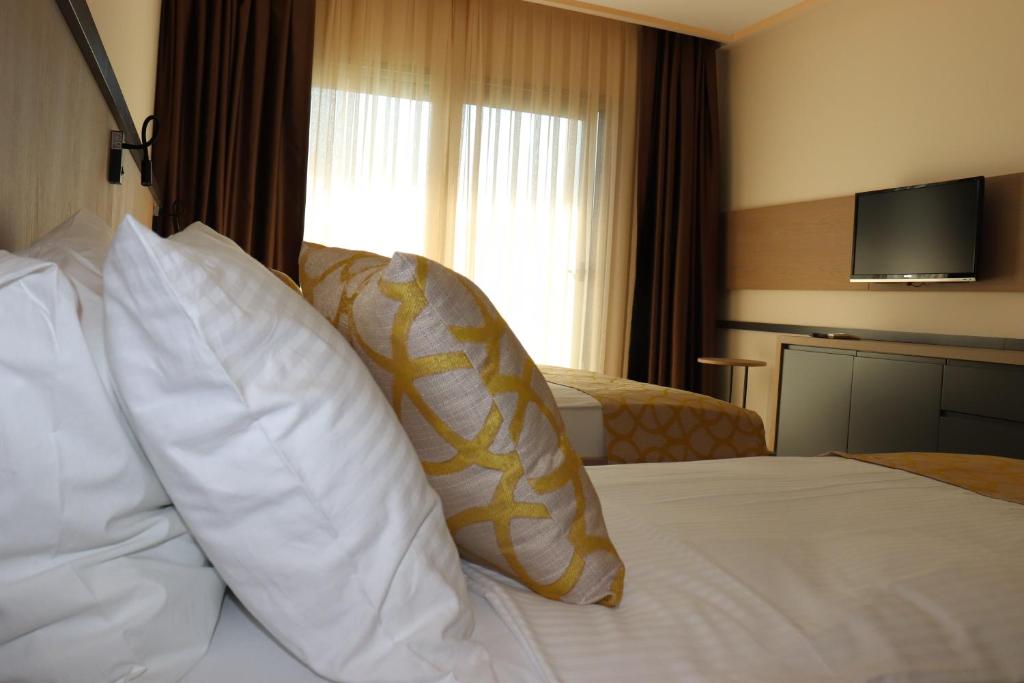 a hotel room with a bed with pillows and a television at Zest Exclusive Hotel & Spa in Ortakent