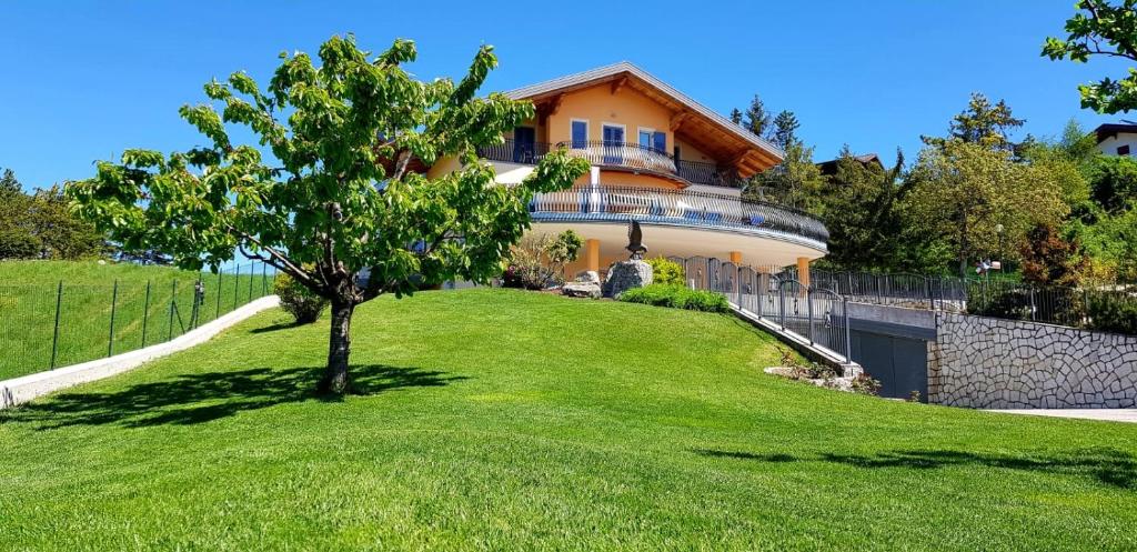 uma casa numa colina com uma árvore no quintal em Affittacamere Dolce Sogno em Coredo