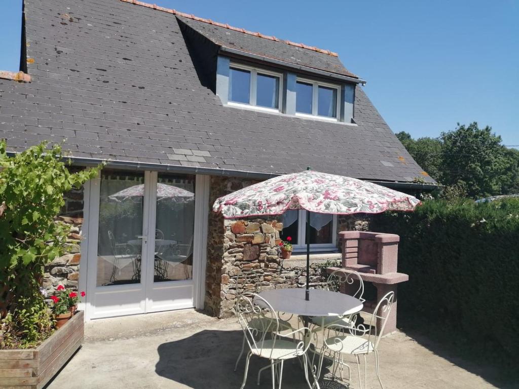 une table avec un parasol devant une maison dans l'établissement La Vieille Ferme, à Donnay