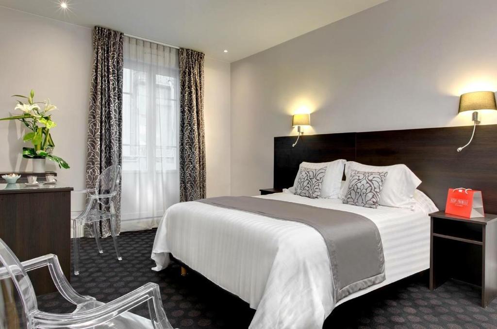 een hotelkamer met een groot bed en een stoel bij Logis Le Midland in Vichy