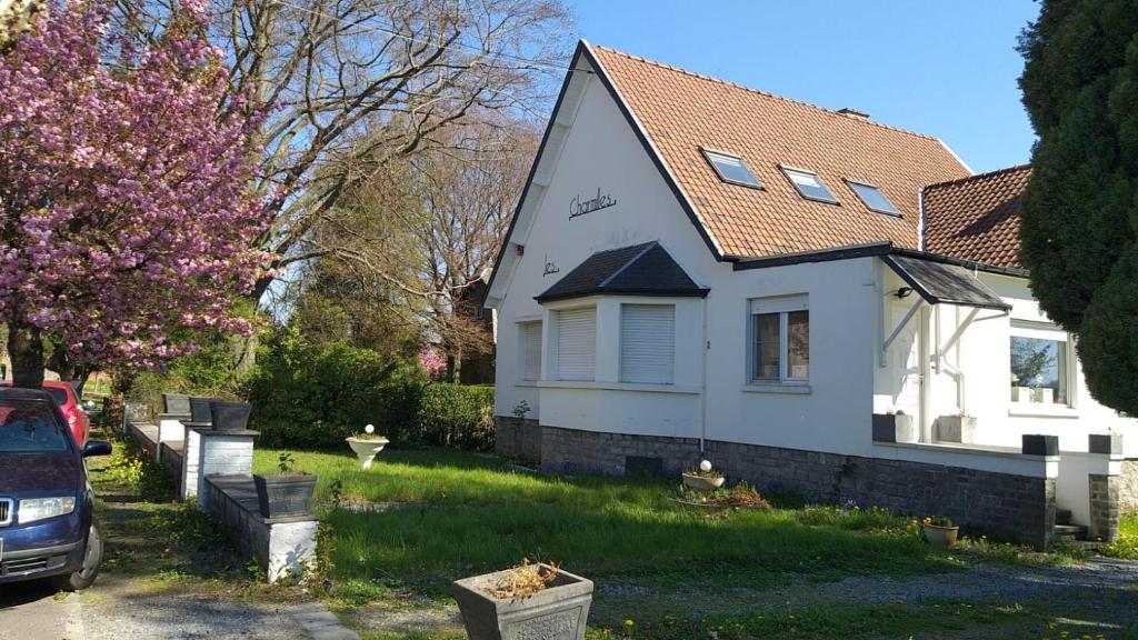 a white house with a car parked in front of it at Les charmilles in Chaudfontaine