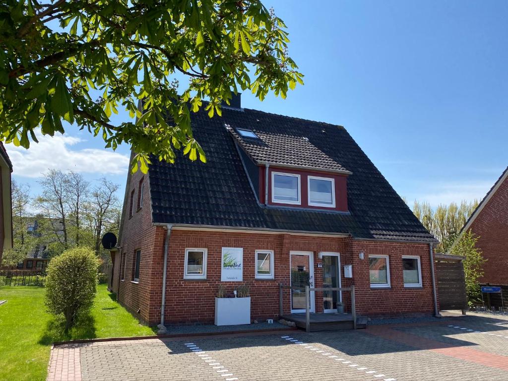 una casa de ladrillo rojo con techo negro en Hotel Garni Dünennest en Sankt Peter-Ording