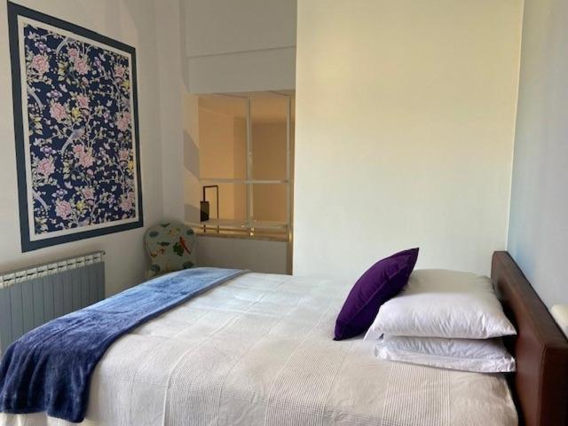 a bedroom with a large bed with purple pillows at Hotel Mambo in Laigueglia