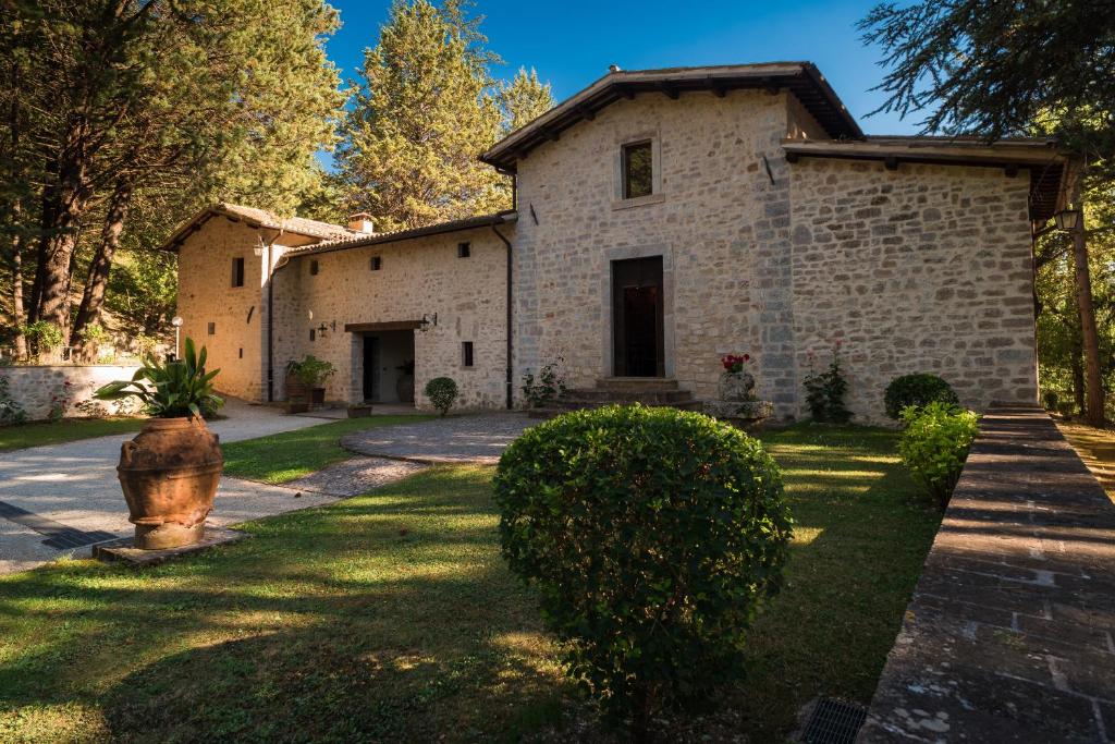 Sellano的住宿－Convento di Acqua Premula，一座大型石屋,设有一座带灌木的庭院