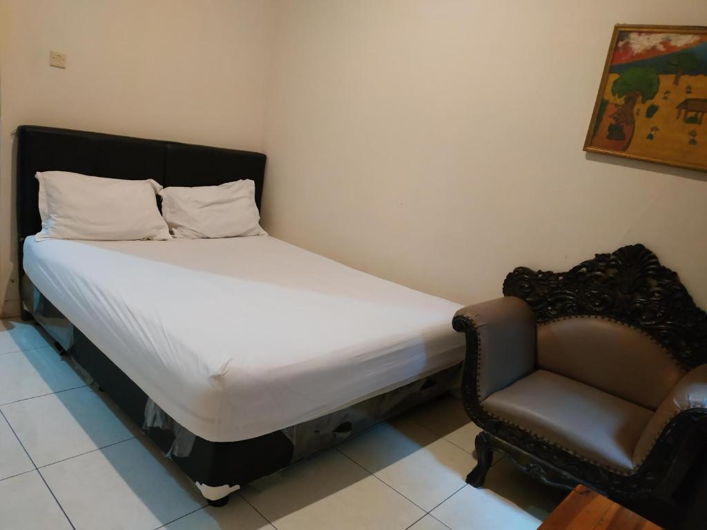 un letto piccolo e una sedia in una stanza di Pemda 22 Mansion Mitra RedDoorz a Bogor