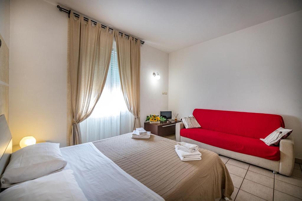 フィレンツェにあるAffittacamere San Jacopinoのベッド2台と赤いソファが備わる客室です。
