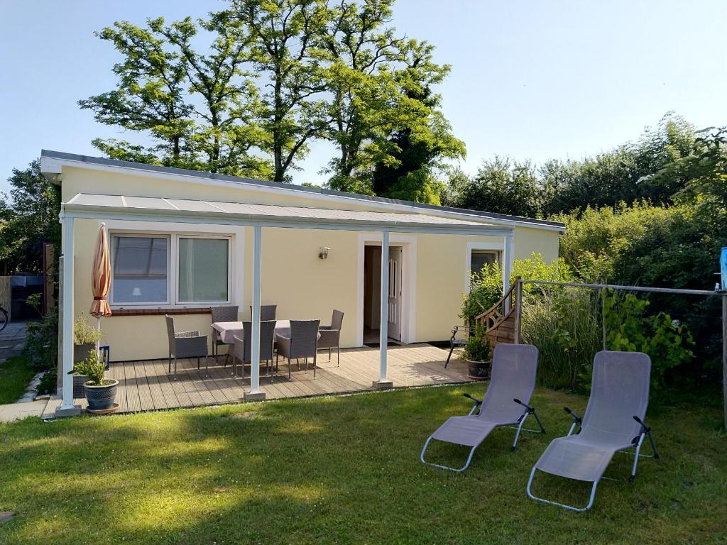 a tiny house with chairs and a table in a yard at Bungalow Bauerngarten in Steffenshagen