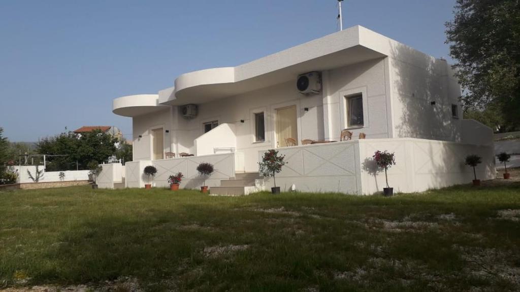 a white house with a grassy field in front of it at Vila Juna in Ksamil