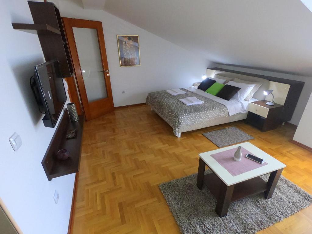 a bedroom with a bed and a table and a tv at Apartman ZENIT in Vrnjačka Banja