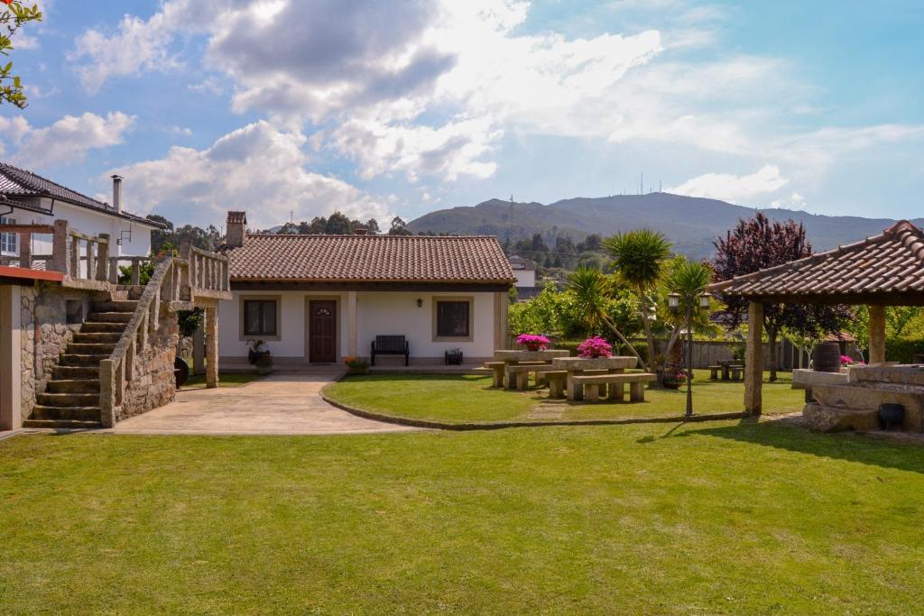 un patio con mesas de picnic y una casa en Casinha do Eido Novo - Alojamento Local en Valença