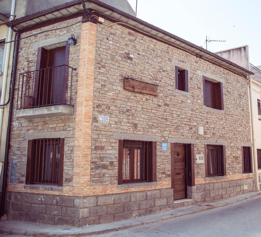 Edificio de ladrillo antiguo con ventanas y balcón en CASA CUATRO ESQUINAS, en Sotillo de la Adrada