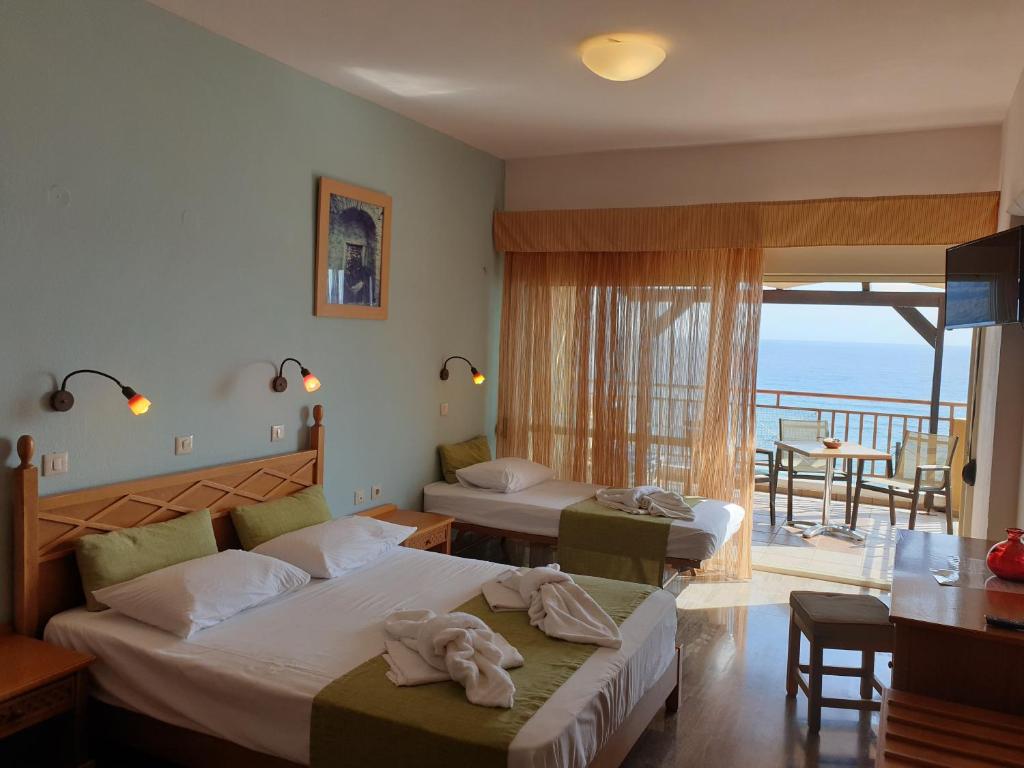 a hotel room with two beds and a balcony at Thalassa House Apartments in Plakias