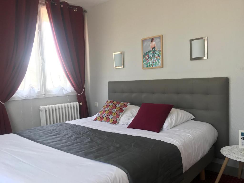 a bedroom with a large bed with a red pillow at Le Canada in Hermanville-sur-Mer