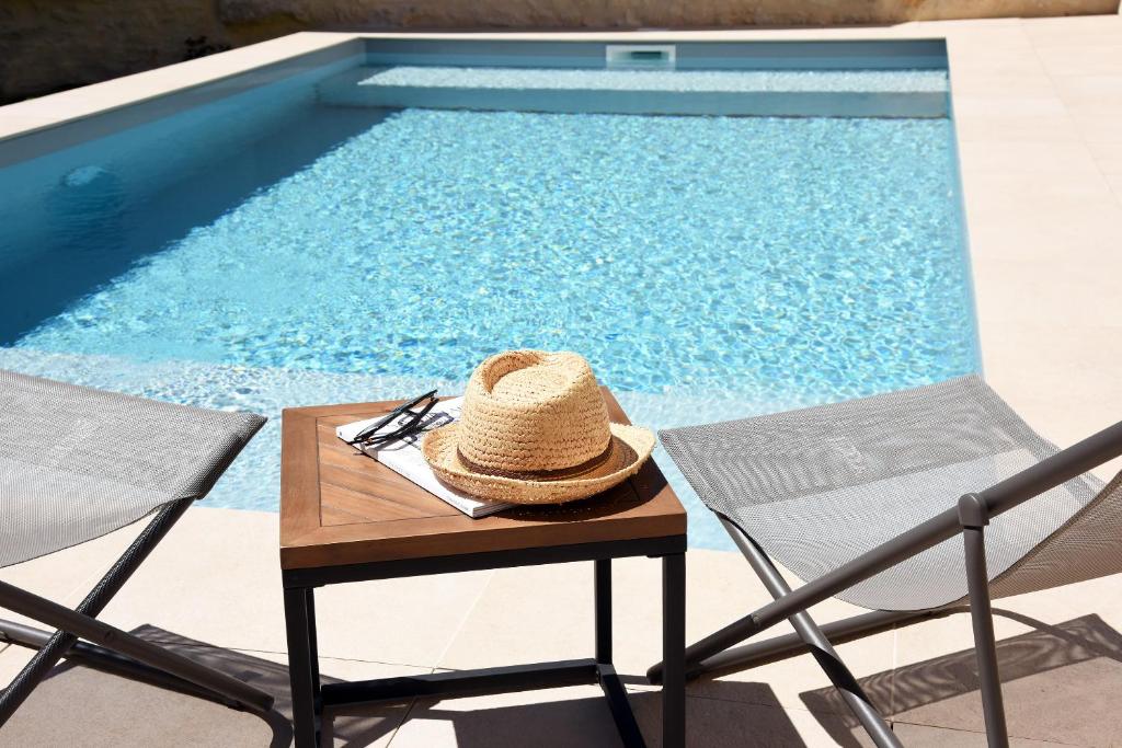 un sombrero de paja sentado en una mesa junto a una piscina en Le Charles V, en Meursault