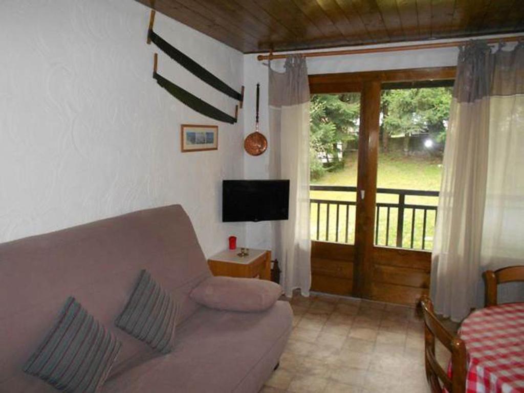 ein Wohnzimmer mit einem Sofa und einer Glasschiebetür in der Unterkunft Chalet de Basseville in Combloux