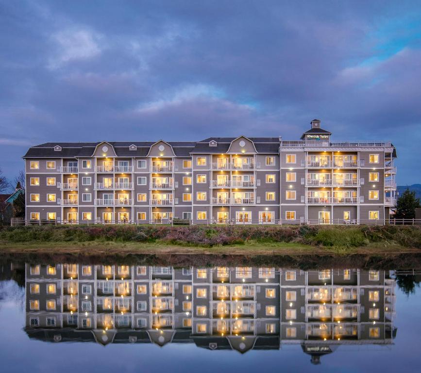 un grand bâtiment avec sa réflexion dans l'eau dans l'établissement Rivertide Suites, à Seaside