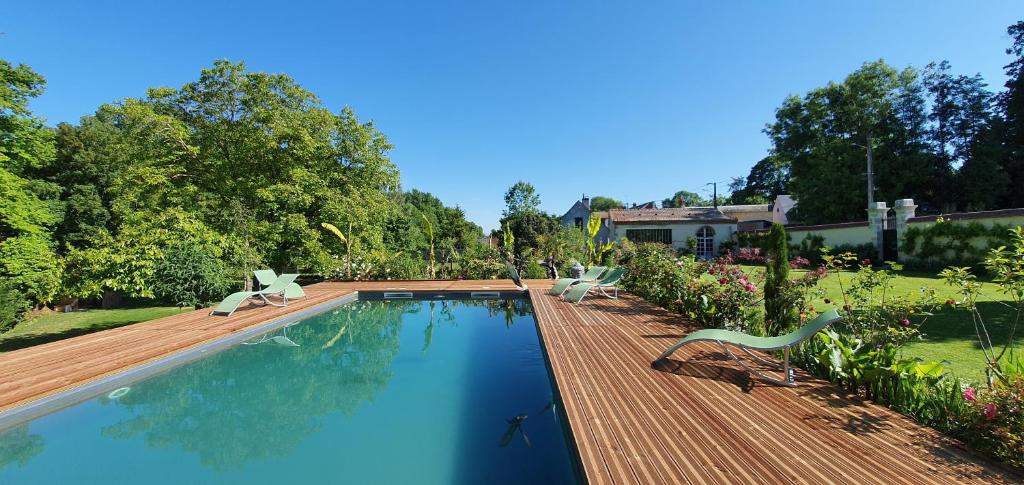 una piscina con 2 sillas y una terraza de madera en La Folie Hubert, en Meung-sur-Loire