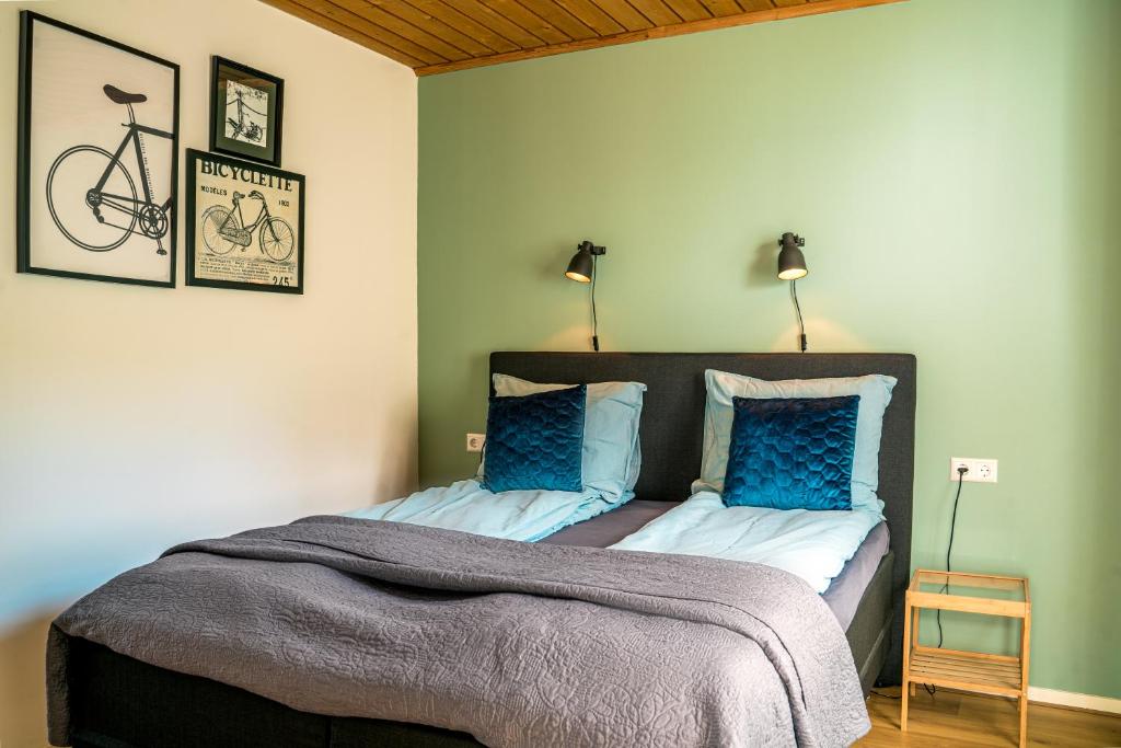 een slaapkamer met een bed met blauwe kussens en een fiets aan de muur bij Bed en Bike Texel in Den Burg