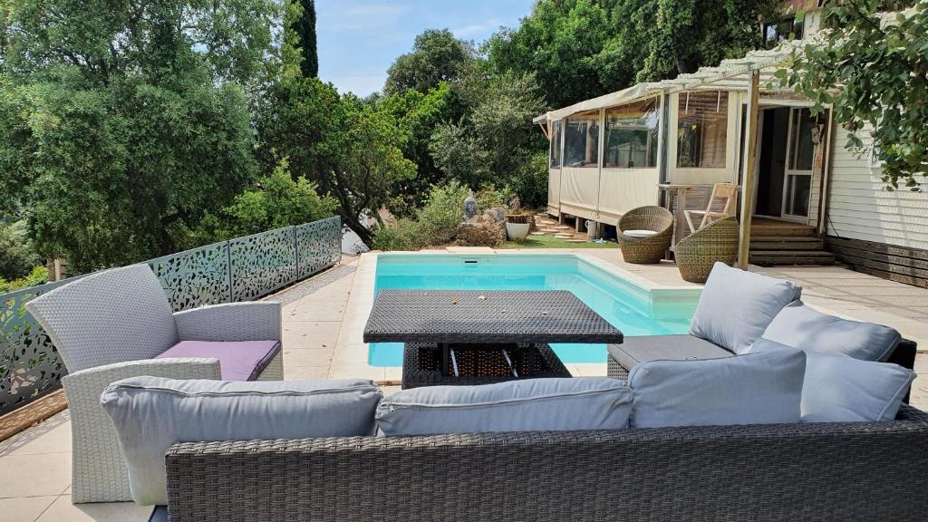 a patio with chairs and a table next to a pool at Mon petit Eden in Le Muy