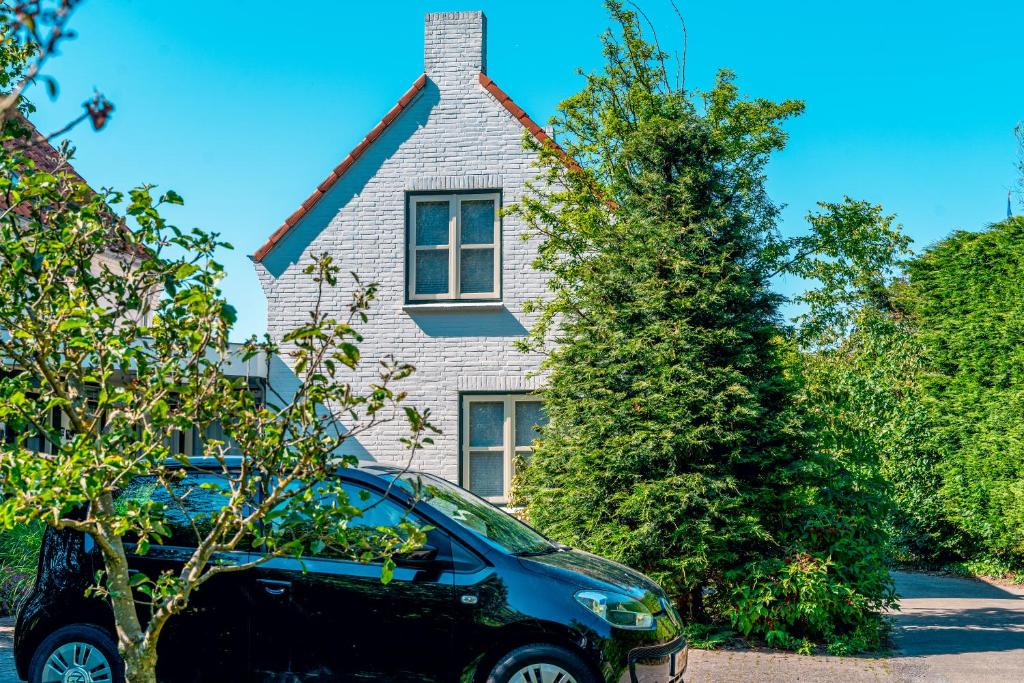 a black car parked in front of a house at Bed en Bike Texel in Den Burg