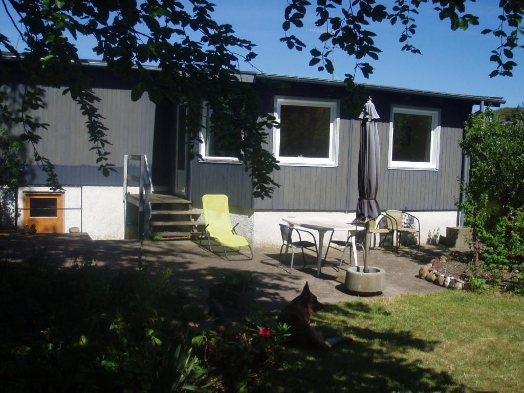 a patio with a table and an umbrella and chairs at "Alléhuset" in Roslev