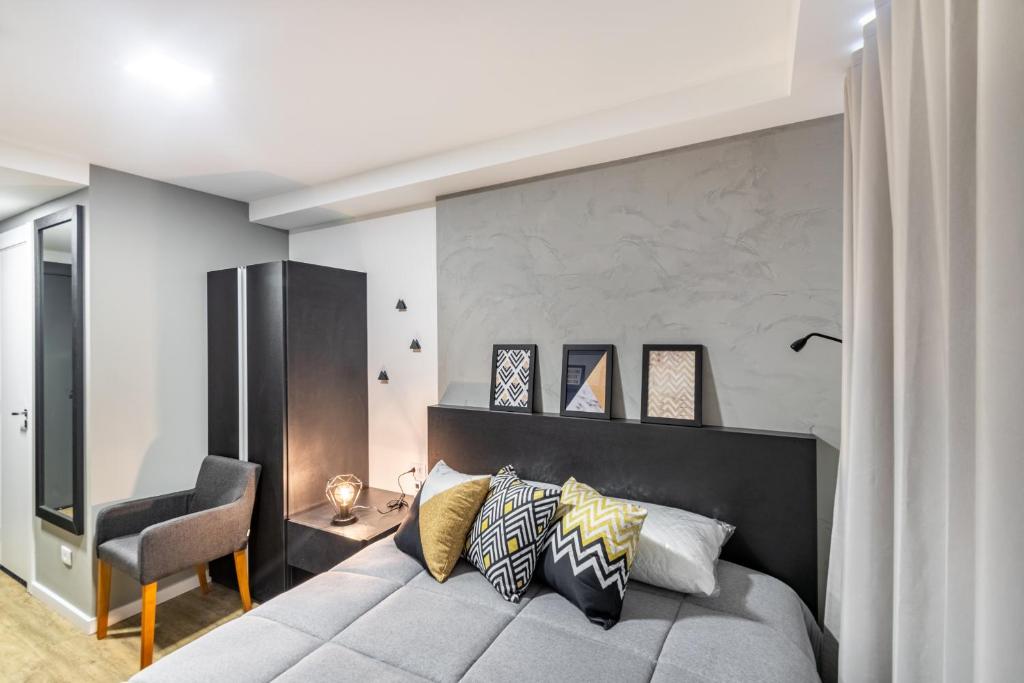 a bedroom with a large bed and a chair at Studio Central e Completo - AYN011 in Curitiba