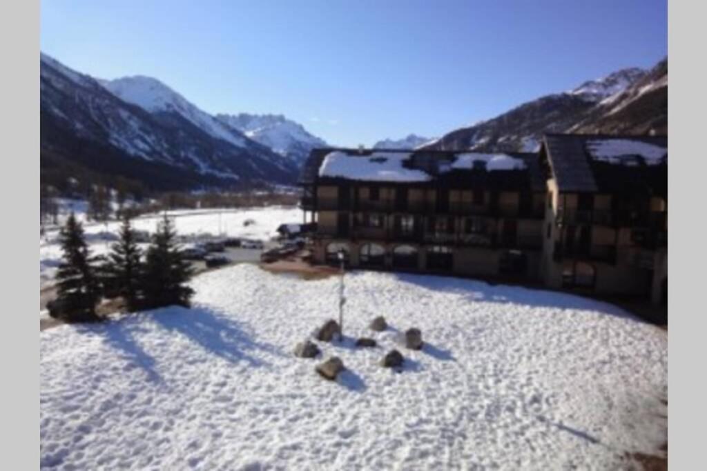 une pile de rochers dans la neige devant un bâtiment dans l'établissement Loue studio de vacances rénové à Névache, à Névache